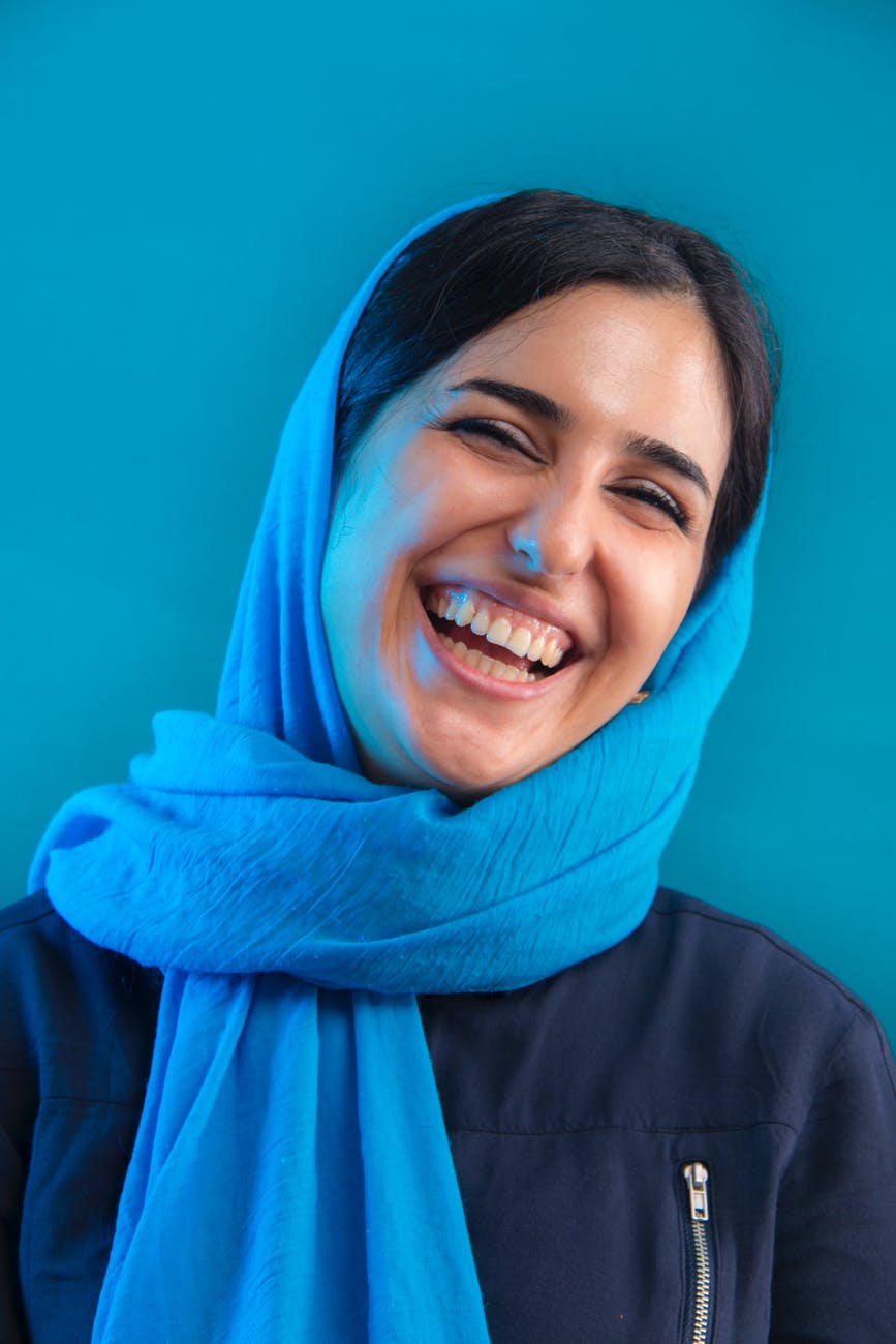 woman leaning on blue wall while smiling