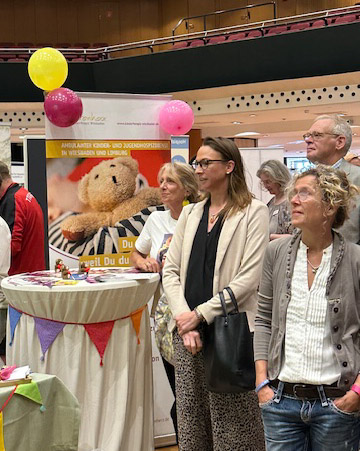 Katrin Schleenbecker und Sabine Häuser-Eltgen stehen im Publikum und hören der Begrüßung zu